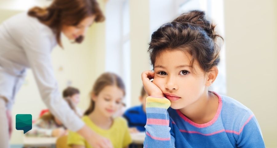 Como motivar alunos desinteressados: menina sentada em uma sala de aula com cara de chateada.