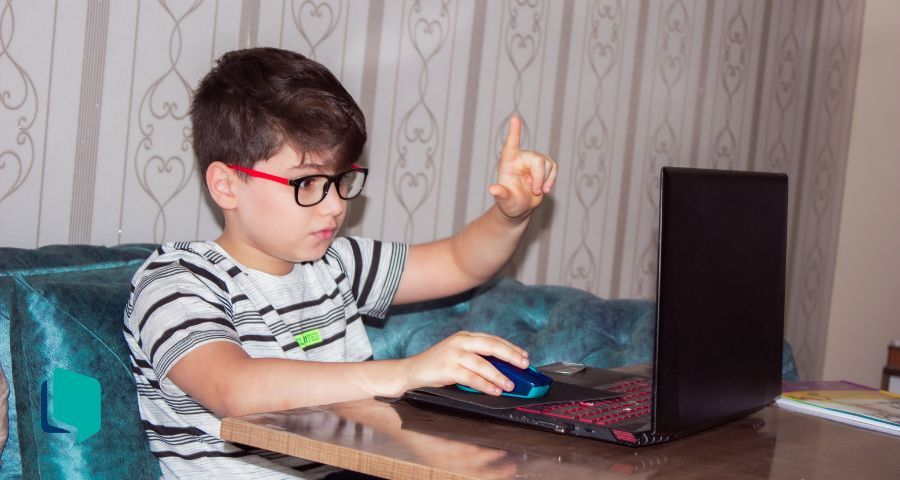 Cultura digital e o ensino de inglês: menino estudando em frente a um computador.