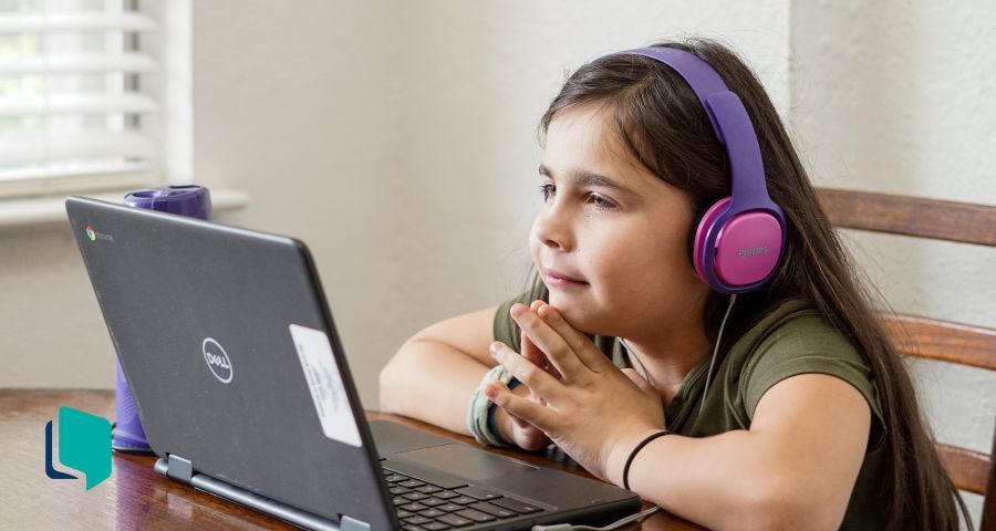 Inglês online para crianças: menina em frente ao computador estudando usando um fone r